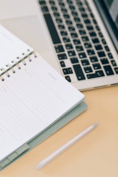 Open notebook next to a laptop and pen on a desk, ideal for business and planning.