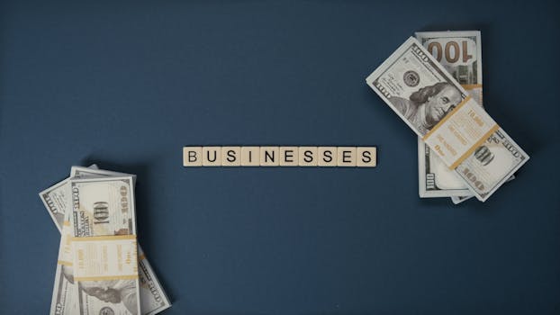 Top view of dollar bills and 'businesses' letter tiles symbolizing financial success.